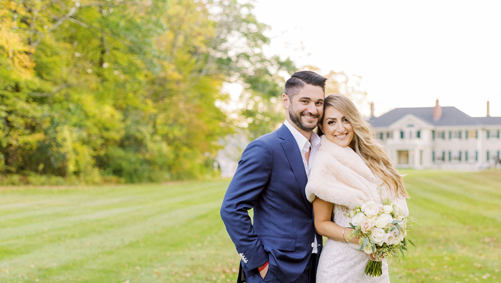 Bride and groom on grass in front of Kimpton Taconic Hotel