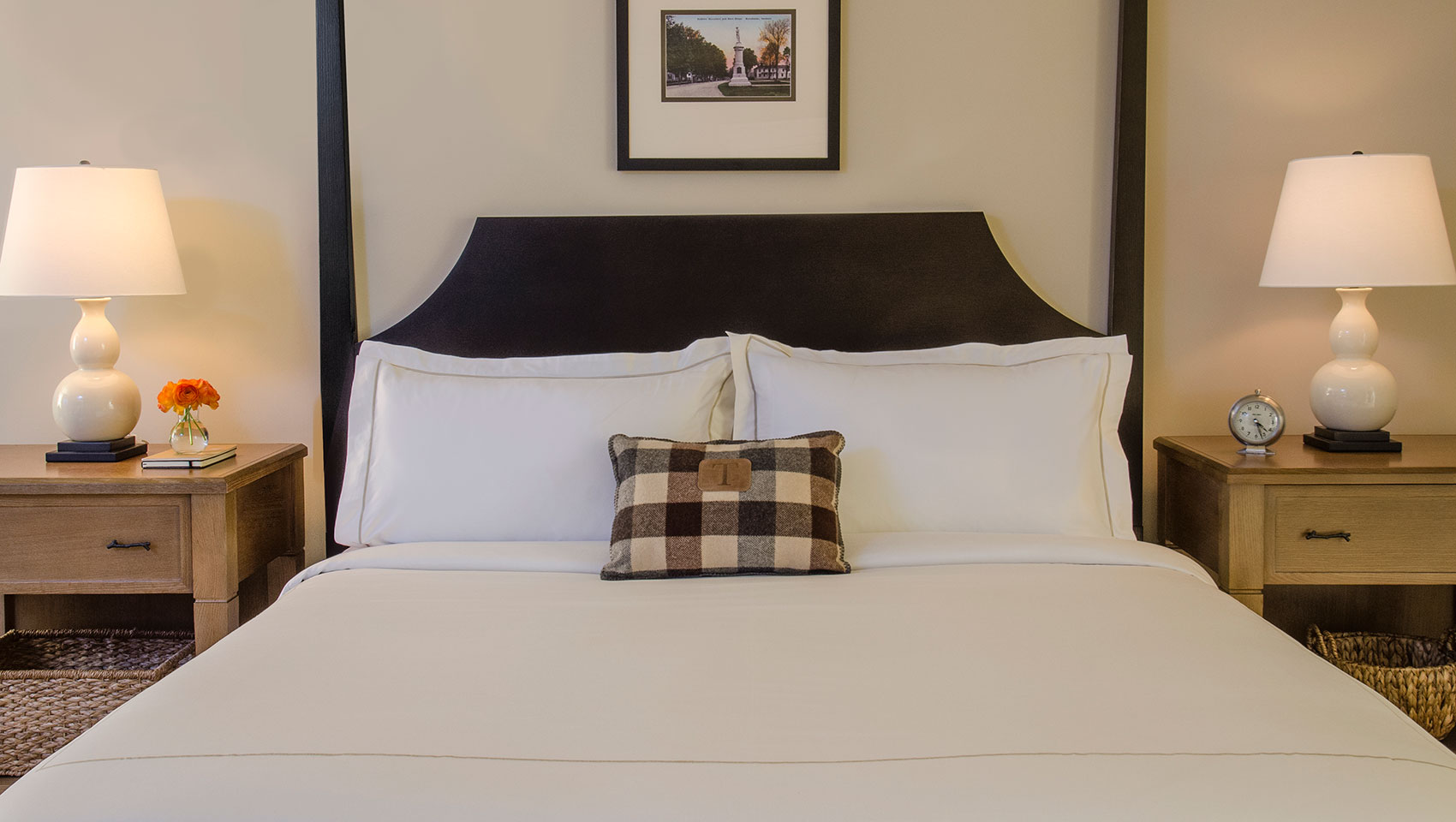 guestroom bed with two side tables, lamps, and throw pillows