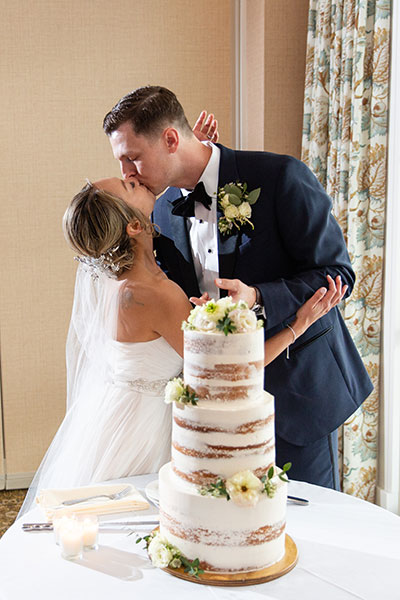 Bride and groom kissing in front of wedding cake