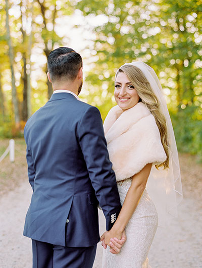 Bride looking at camera while holding groom’s hand