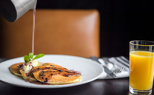 Syrup being poured on pancakes